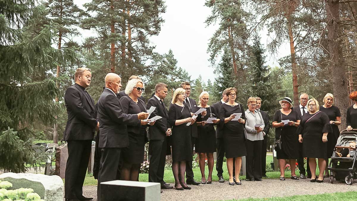 Hautajaisvieraita hautausmaalla.