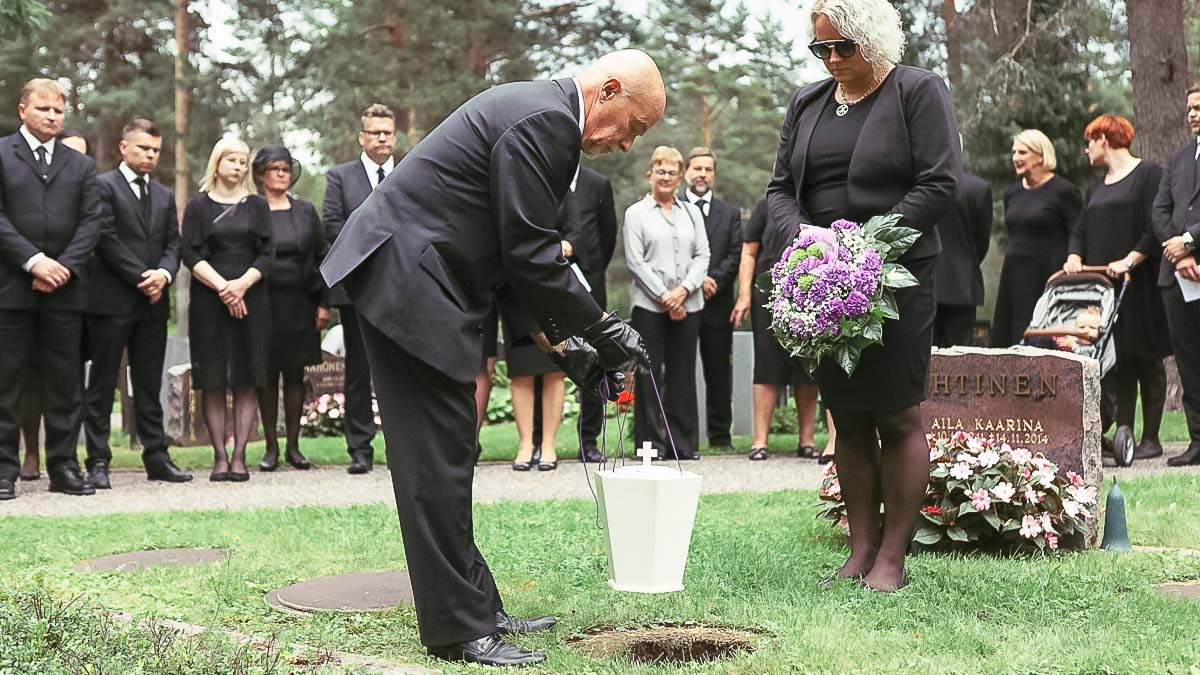 Ihmisiä uurnan hautaamisessa.